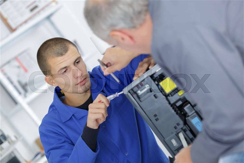 Apprentice working on electrical appliance, stock photo