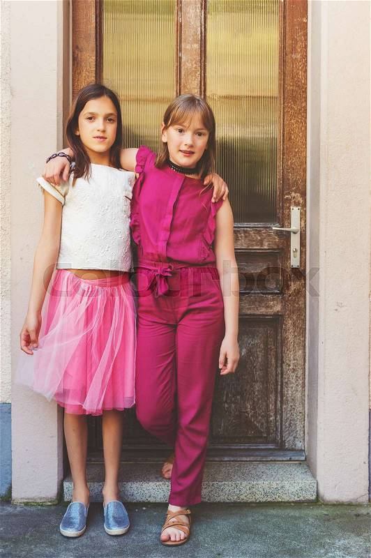 Outdoor fashion portrait of two fashion preteen girls, stock photo