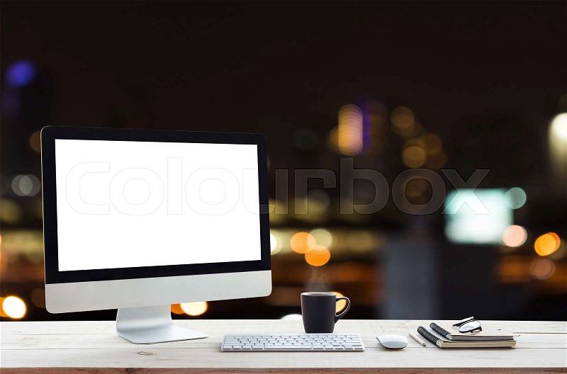 Desktop computer on work table and city night background, stock photo