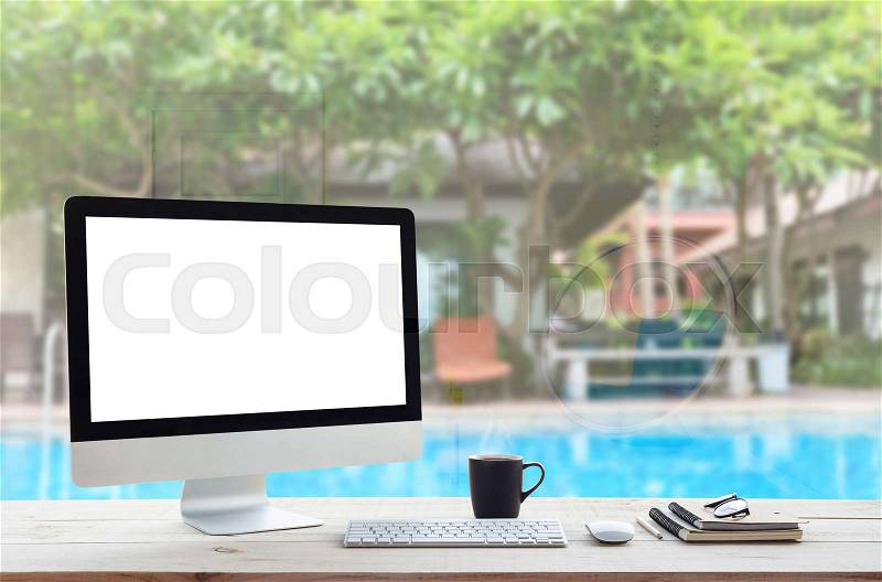 Desktop computer on work table and see through resort hotel background, stock photo