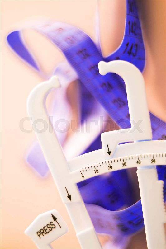 Fat caliper and measuring tape used to measure waistline, bodyfat levels for fitness and obesity checks, stock photo