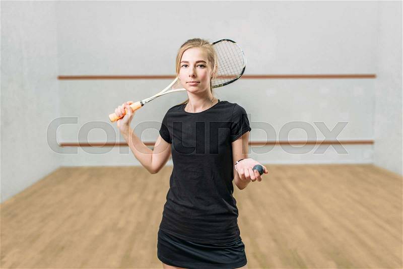Squash game female player with racket and ball in hands, indoor training club on background, stock photo