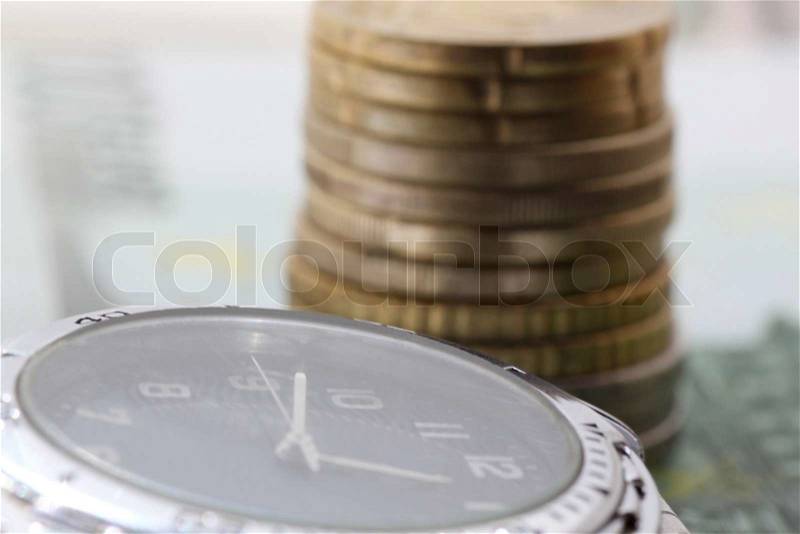 Time is money - watch in front of pile of euro coins, stock photo