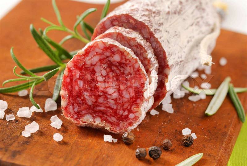 French dry cured sausage with spices on wooden cutting board - close up, stock photo