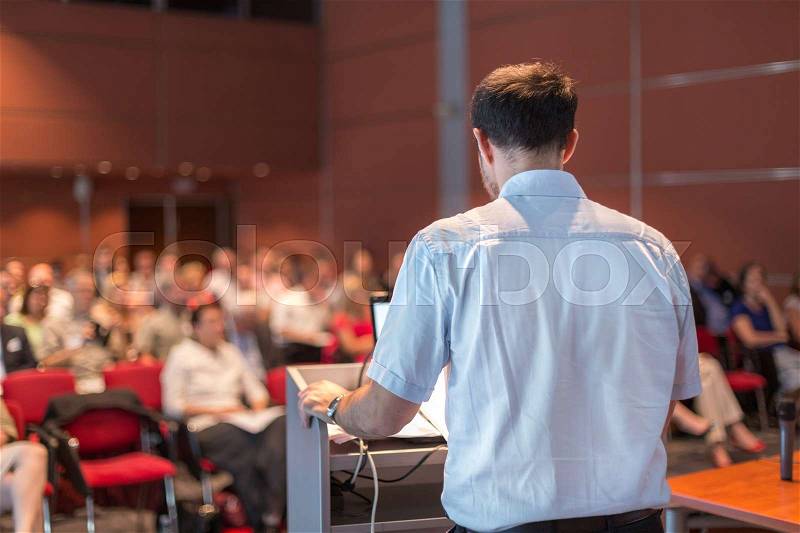 Casualy dressed professor giving talk at scientific conference. Audience at the conference hall. Research experts and entrepreneurship event, stock photo