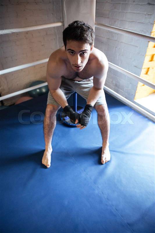 Top view of man boxer sitting in the corner of ring, stock photo
