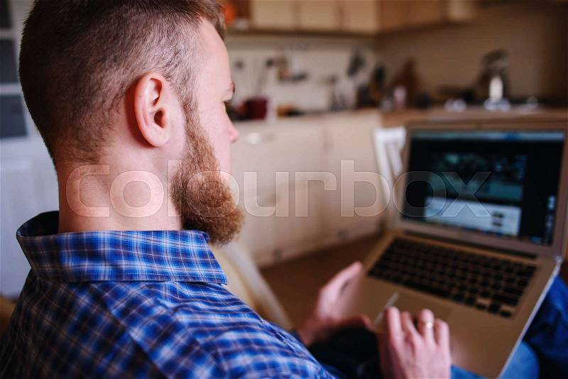 Young man working with computer on the beach. Handsome man working with laptop laying on the couch at the beach, stock photo