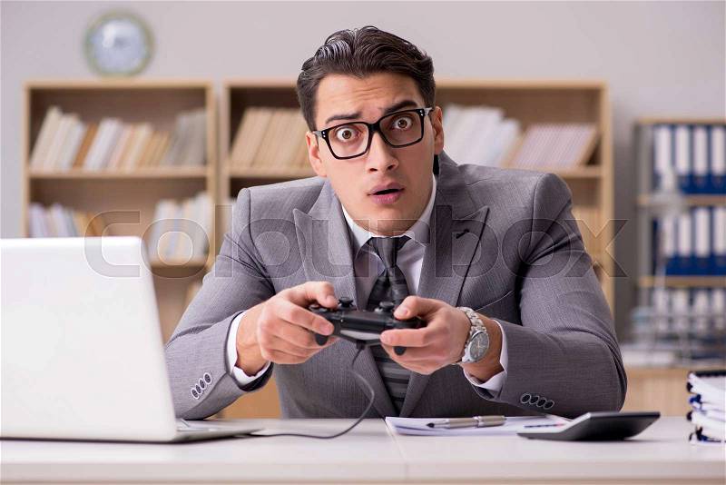 Businessman playing computer games at work office, stock photo