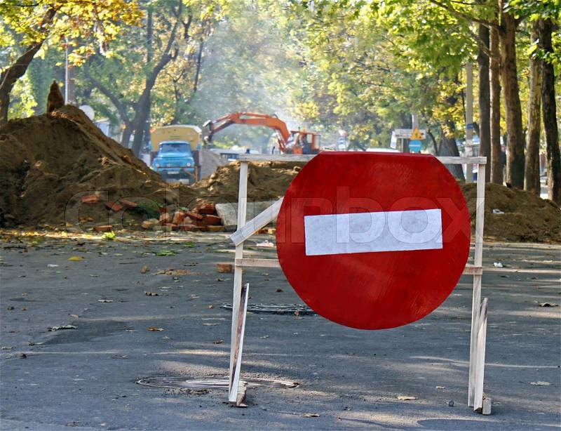 Do not enter sign before heap of ground and a pit on a road, stock photo