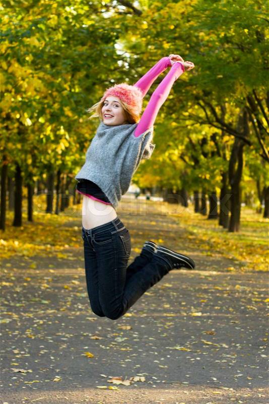 Joyful young woman jumping in the park, stock photo