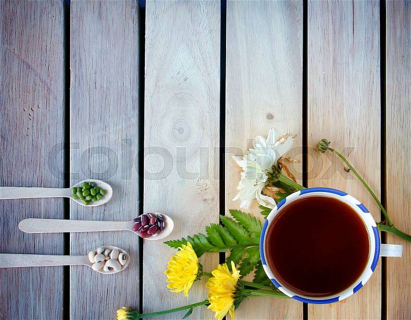 A cup of tea with flowers and tea around it are on wooden background, stock photo
