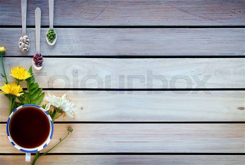 A cup of tea with flowers and tea around it are on wooden background, stock photo