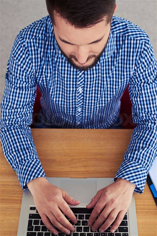 Vertical of mature guy printing in laptop in bright room, stock photo