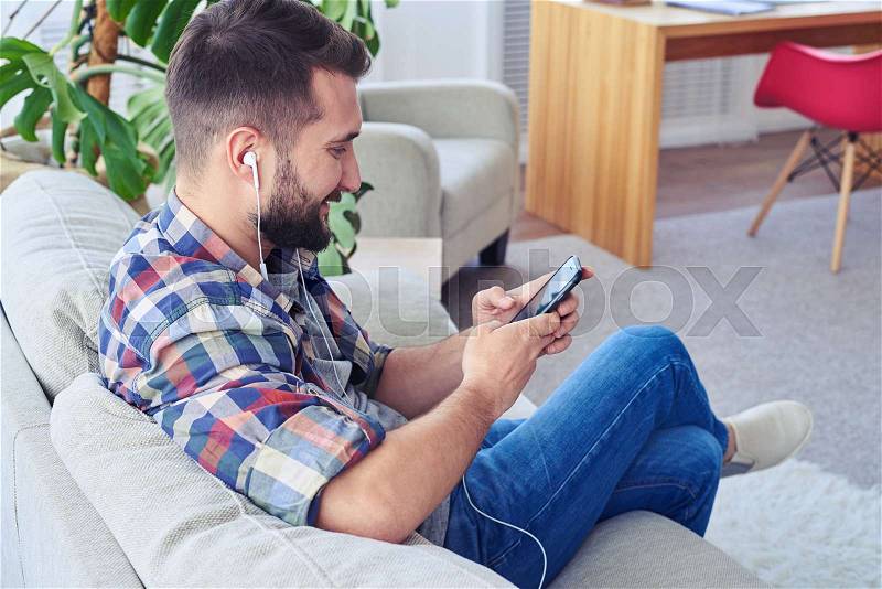 Mid shot of bearded guy relaxing and listening to music, stock photo