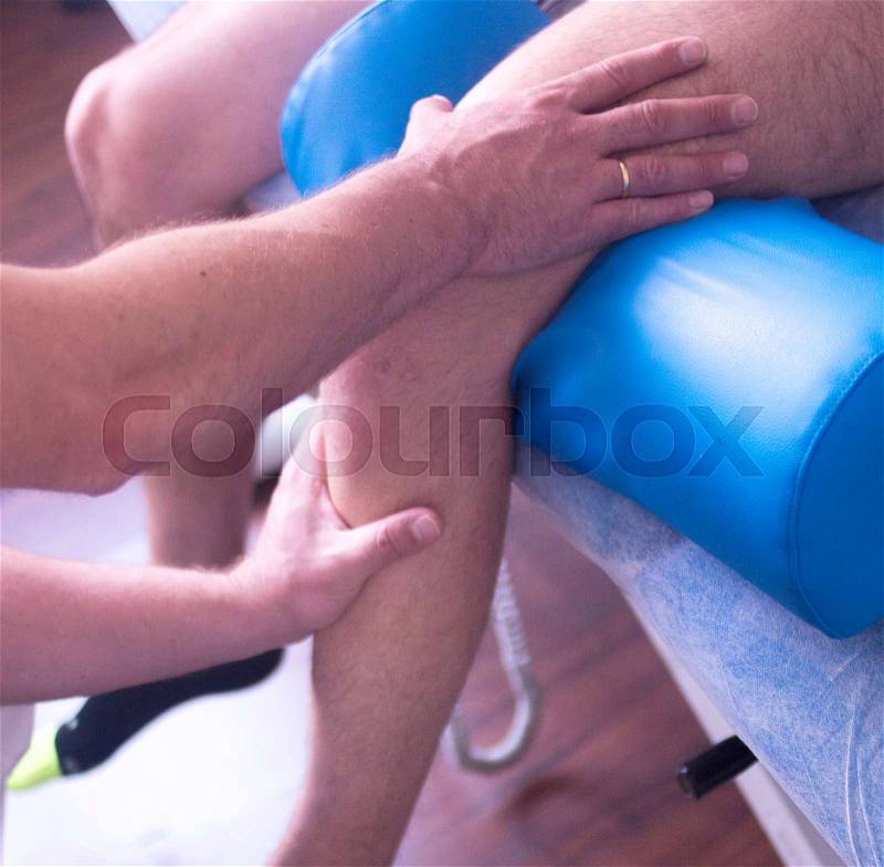 Physical therapy manual physiotherapy treatment by physiotherapist on patient for knee inury rehabilitation, stock photo
