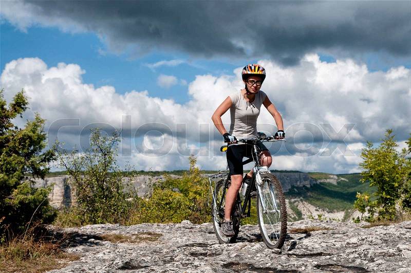 Young athletic girl rides a bicycle on a mountain road, stock photo