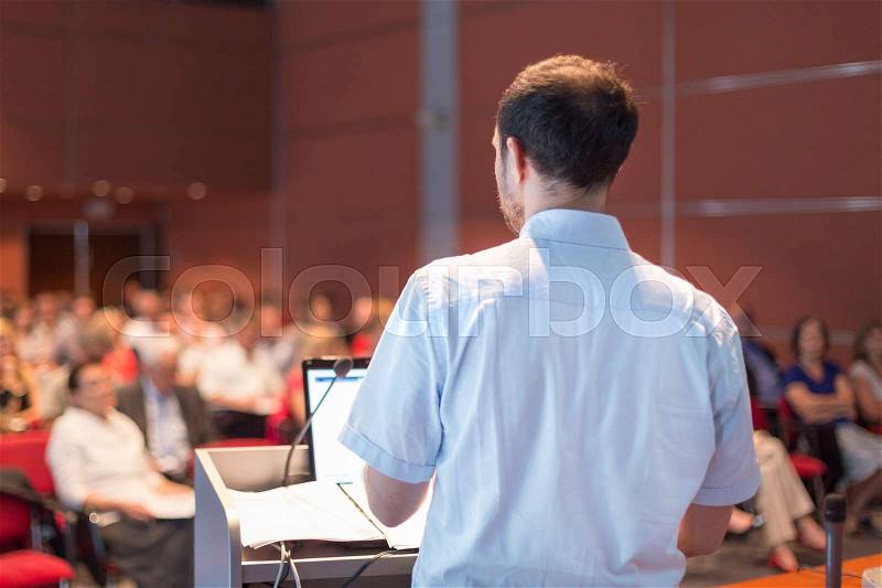 Casualy dressed professor giving talk at scientific conference. Audience at the conference hall. Research experts and entrepreneurship event, stock photo