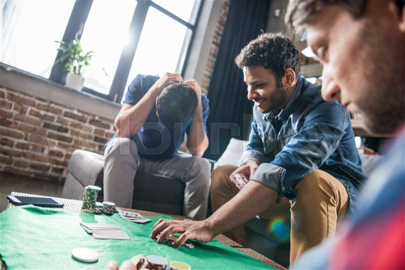 Young men playing cards at gaming table, young people having fun concept, stock photo