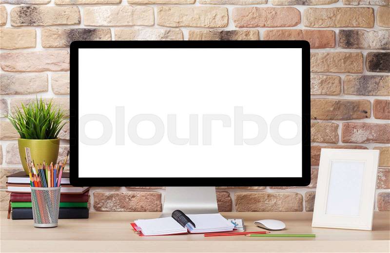 Office desk workplace with pc in front of brick wall. Loft style, stock photo