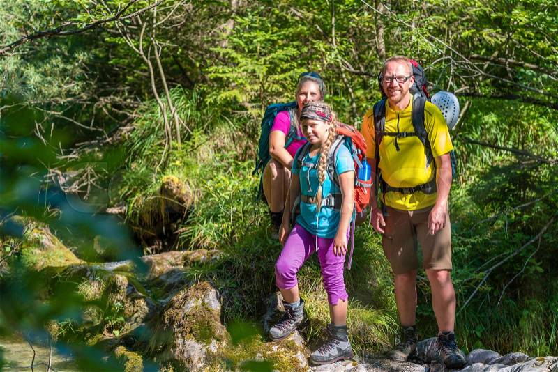 Family on a hike standing close to river, stock photo