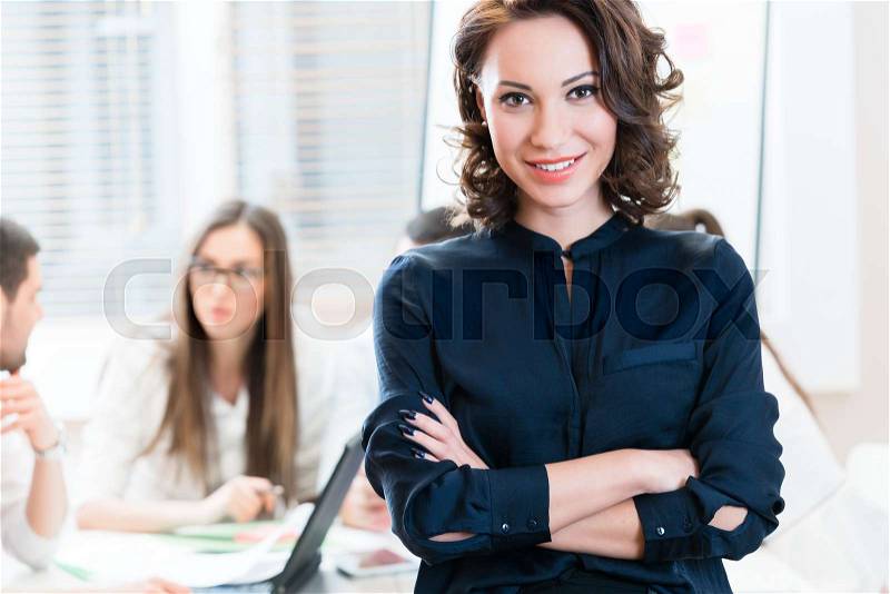 Manager with her team working in the office looking into camera, stock photo