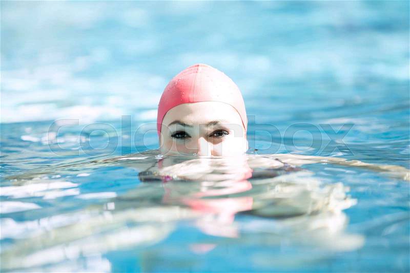 Beautiful woman cap smiling looking to camera at border of swimming pool, stock photo