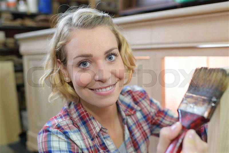 Portrait of woman painting a cupboard, stock photo