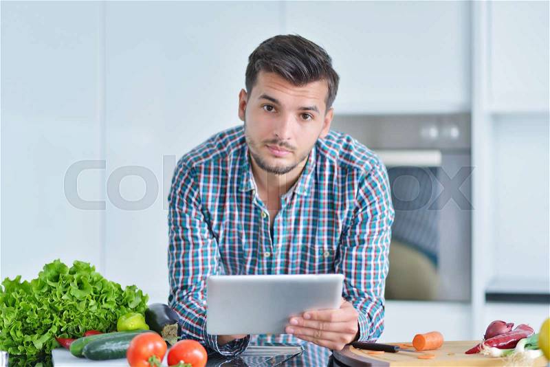 Happy man using digital tablet in kitchen at home, stock photo
