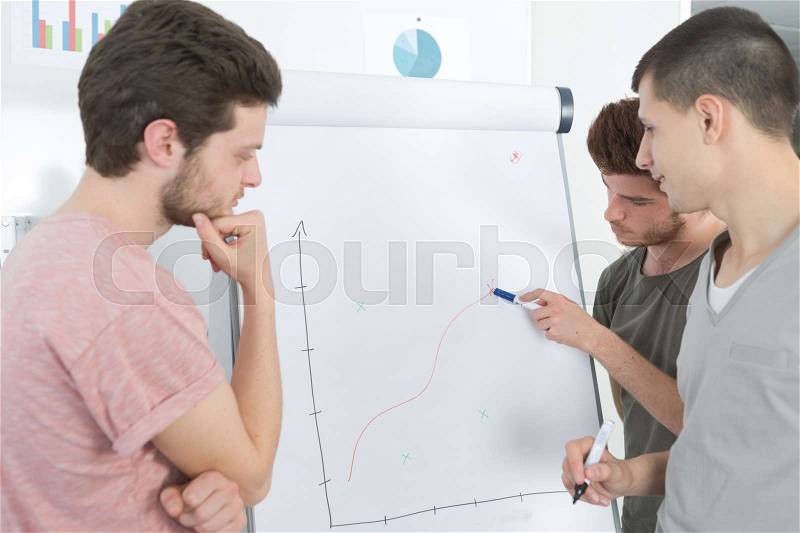 Young men tracing graph on flip chart, stock photo