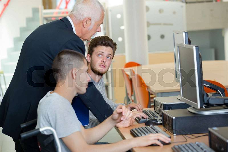 Teacher advising student using computer, stock photo