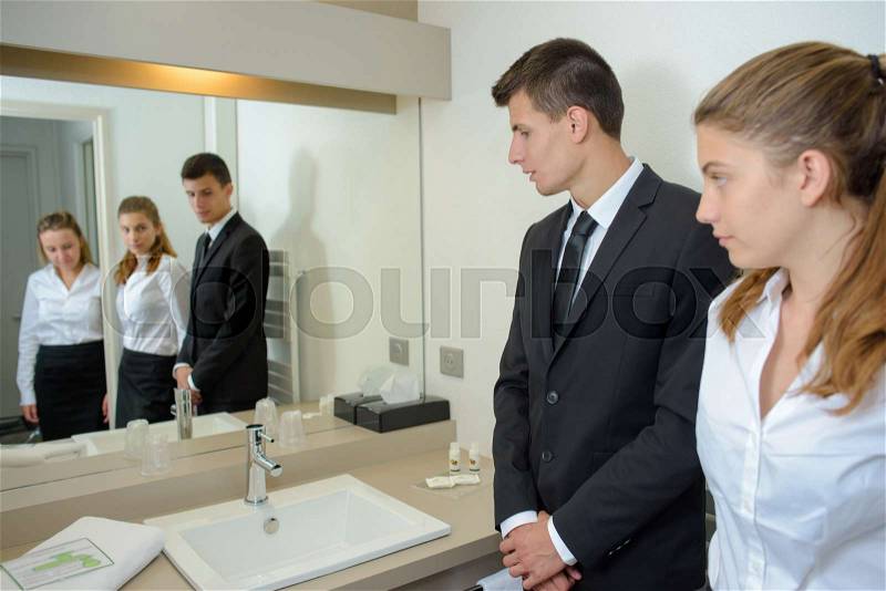Hotel staff reflected in bathroom mirror, stock photo