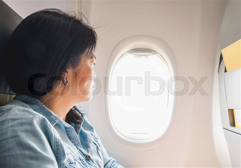 Asian Woman sitting at window seat in airplane and look outside window.traveling concept, stock photo