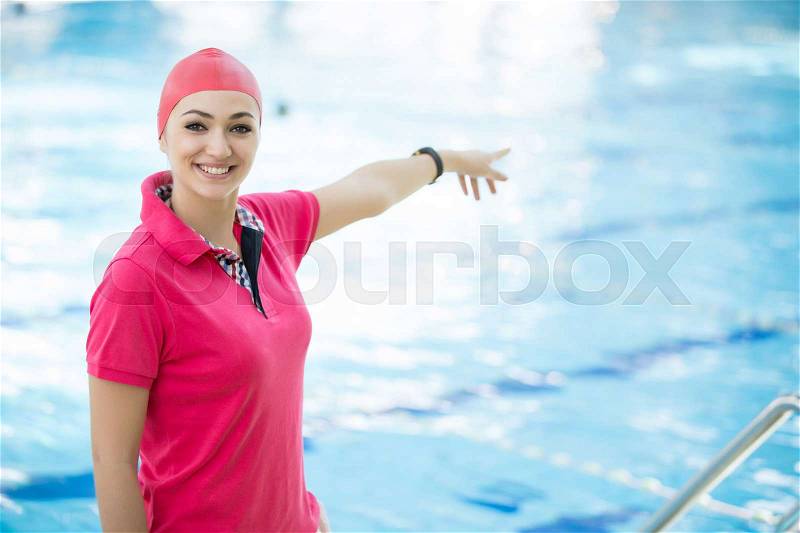 Portrait of female coach with a stop watch and clipboard by pool at leisure center, stock photo