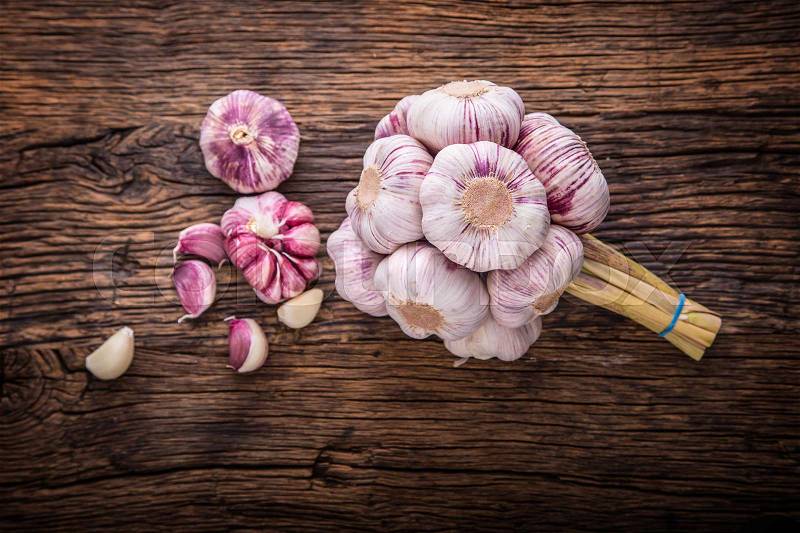 Garlic. Fresh garlic bulbs on old wooden board. Red violet garlic, stock photo