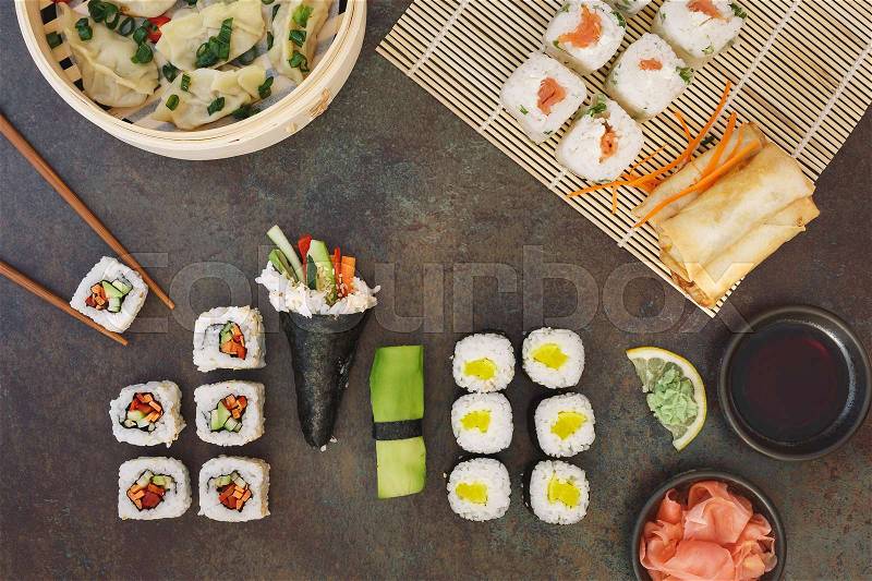Various sushi, Japanese lunch and side dishes and dipping sauces on dark background. Top view, blank space, stock photo