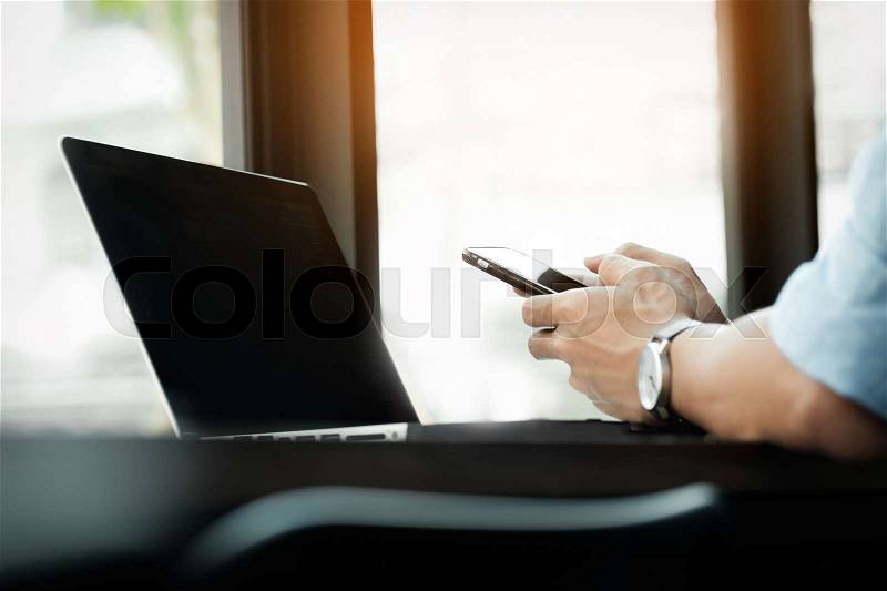 Smiling young casual business man with mobile phone in the hand in office, stock photo
