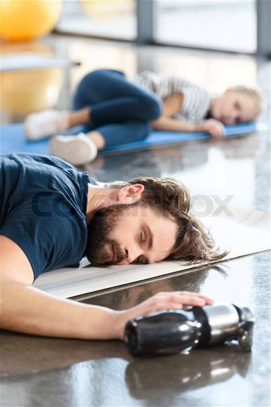 Tired sleeping man lying on mat at gym, stock photo