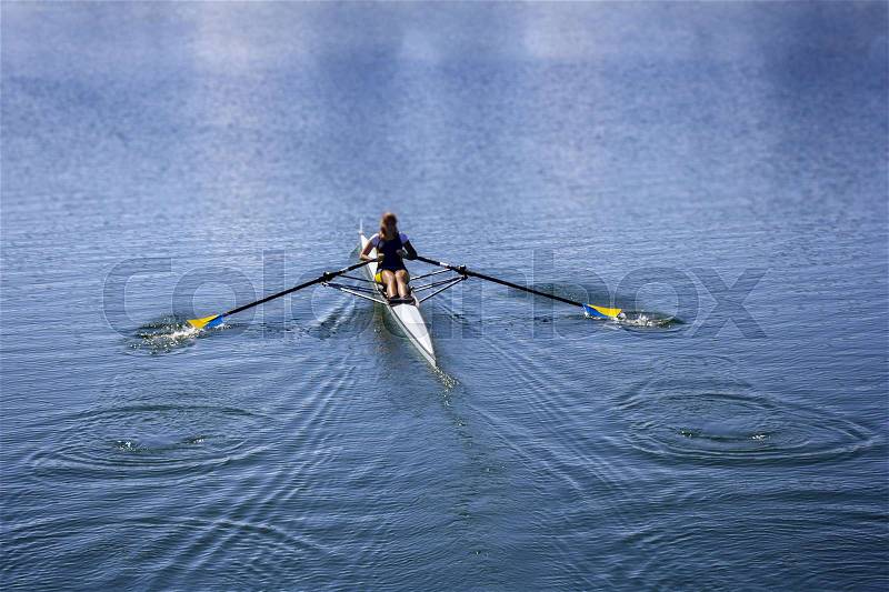 Young woman rowing in boat on the lake, stock photo