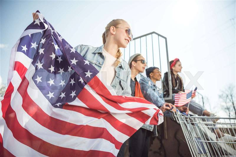 Happy teenagers group having fun and waving american flags at sunset, stock photo