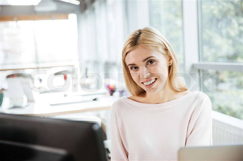 Photo of young cheerful lady sitting in office coworking using computer. Looking aside, stock photo