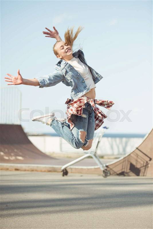 Stylish teenage girl jumping at skateboard park, hipster style concept, stock photo