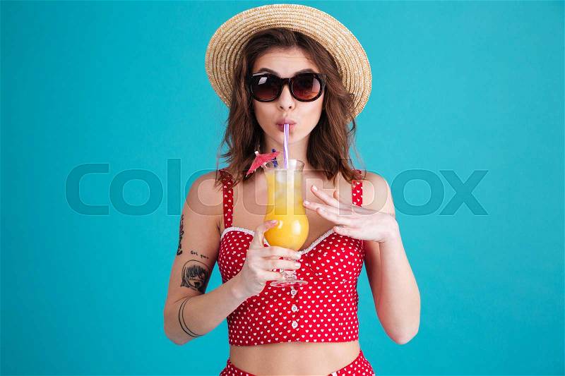 Image of beautiful young lady with cocktail looking at camera isolated over blue background, stock photo