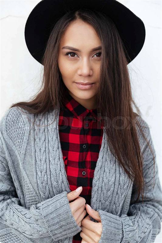 Portrait of beautiful woman wearing hat starring at camera in the street, stock photo