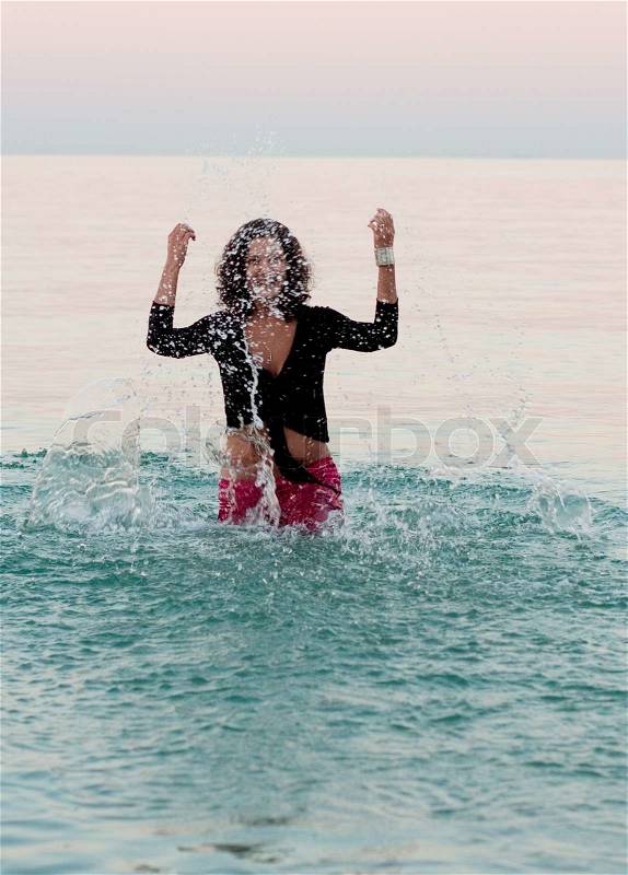Attractive brunet woman in wet clothes splashing, stock photo