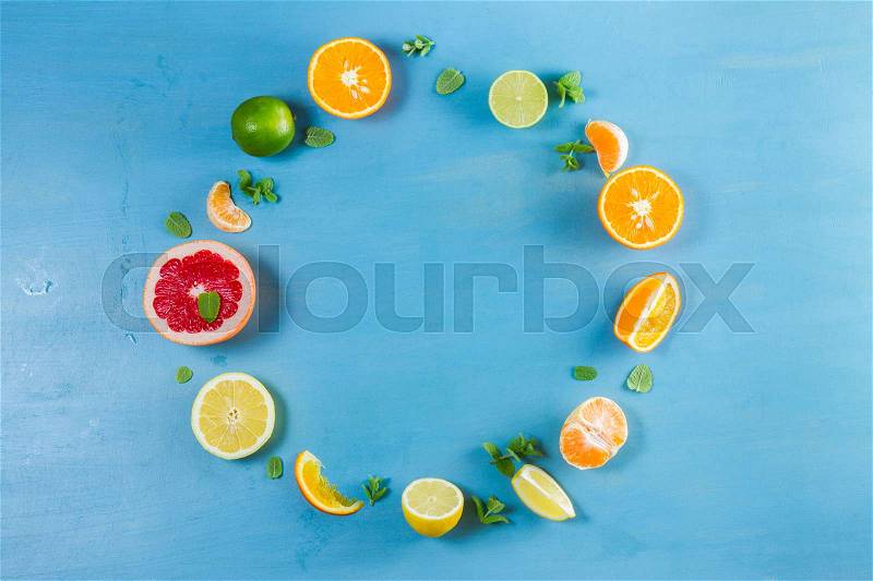 Citrus food circle frame pattern on blue background - assorted citrus fruits with mint leaves, stock photo