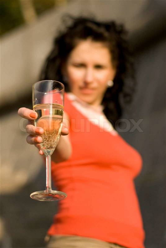 Outdoor portrait of woman with champagne glass, focus on glass, stock photo
