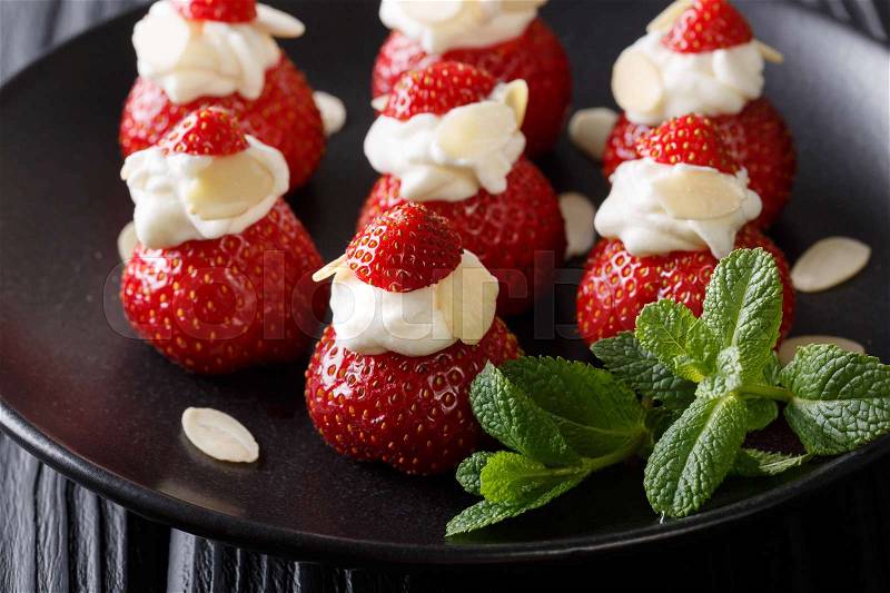 Celebratory dessert from a strawberry stuffed with whipped cream, almonds and mint closeup on a plate. horizontal , stock photo