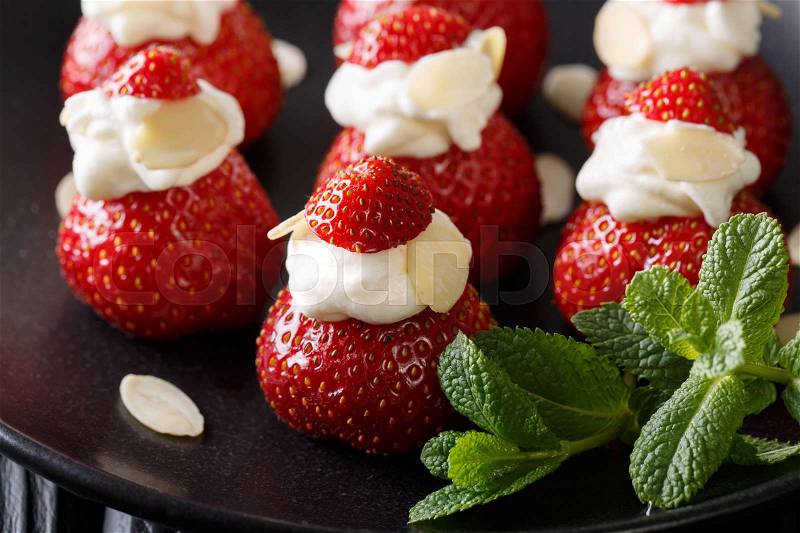 Organic strawberry stuffed with whipped cream, almonds and mint closeup on a plate. horizontal , stock photo