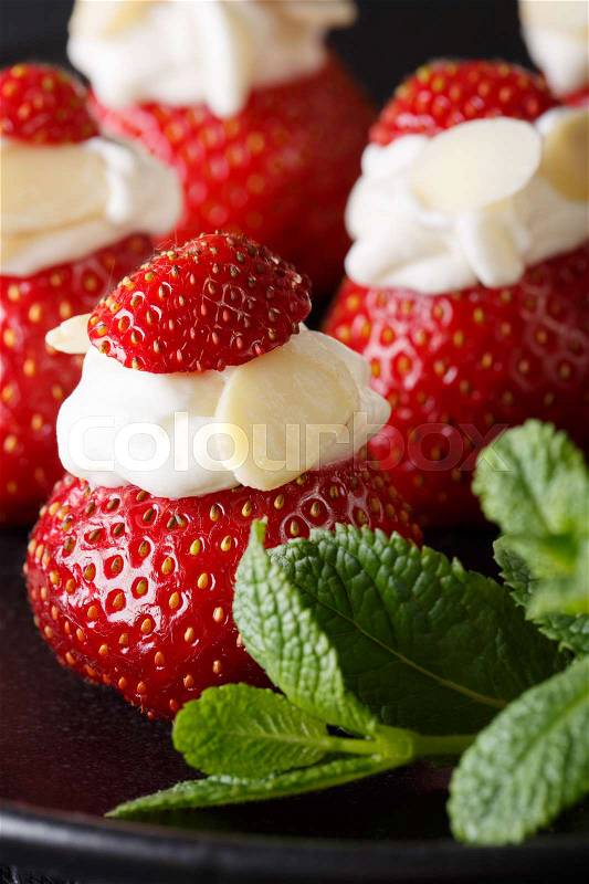 Fresh strawberry stuffed with whipped cream and almond macro on a plate. vertical , stock photo