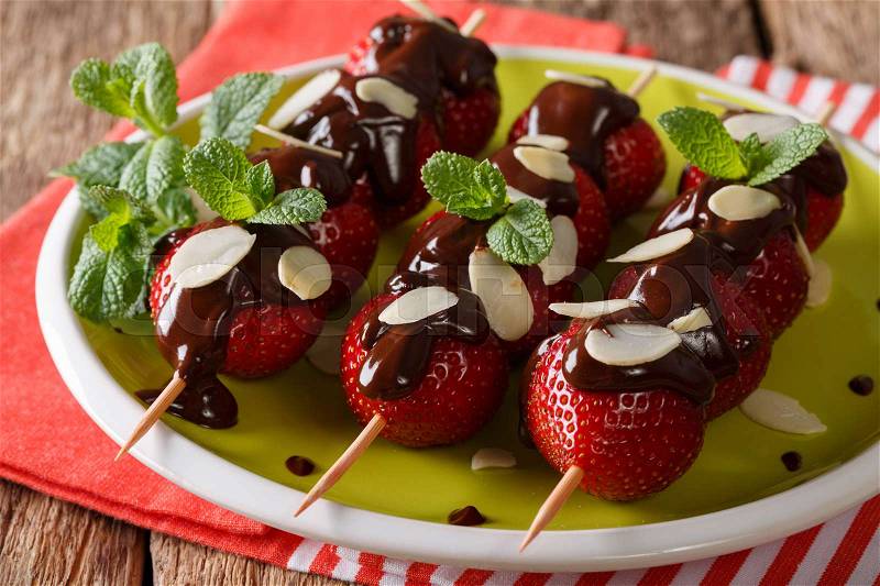 Festive dessert of strawberries decorated with chocolate, mint and almonds close-up on a plate. horizontal , stock photo